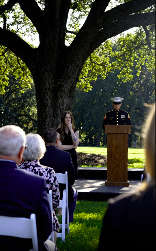 She Stood in the Shadows of the SEAL Memorial, Trying to Remain Invisible. Then the Commander Spotted the Ink on Her Arm, Froze Mid-Speech, and the Entire Ceremony Went Silent.